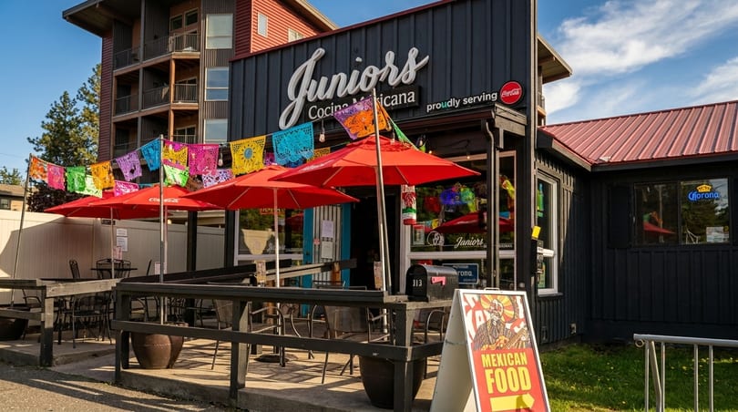 Junior's Cocina Mexicana restaurant exterior with outdoor patio, red umbrellas, and colorful papel picado.