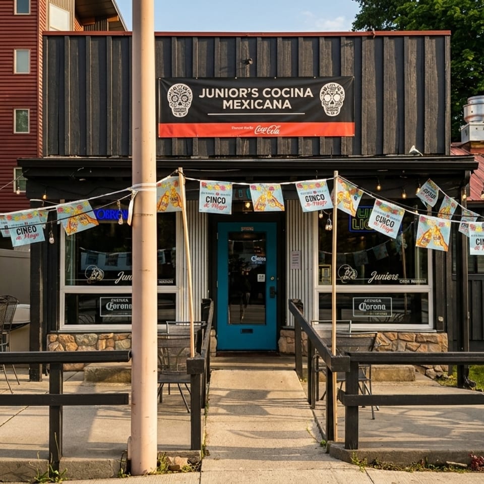 Junior's Cocina Mexicana restaurant exterior with outdoor seating, a blue door, and festive Cinco de Mayo banners.