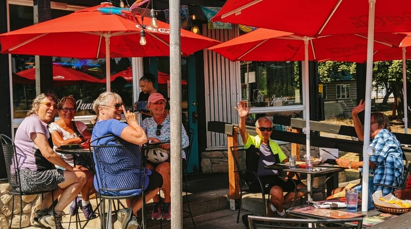 Patrons enjoying outdoor dining under red umbrellas at Juniors restaurant on a sunny day.