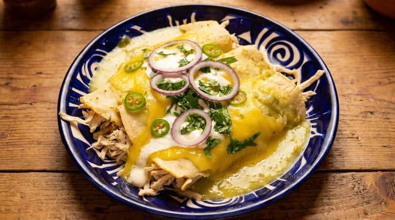 Chicken enchiladas with green sauce, cheese, sour cream, red onion, cilantro, and jalapeños.